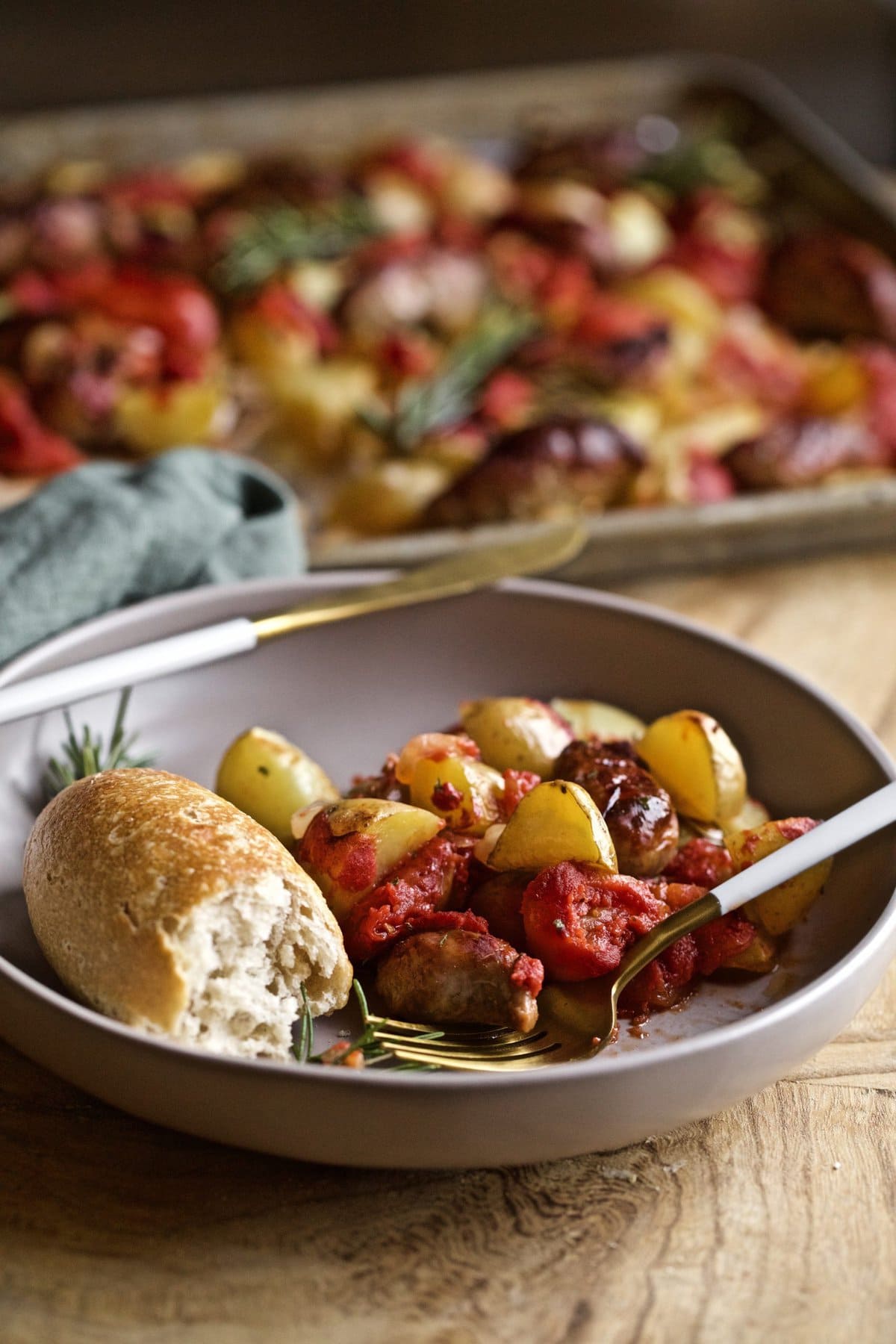 Italian sausage and potatoes on a plate with bread and a fork.