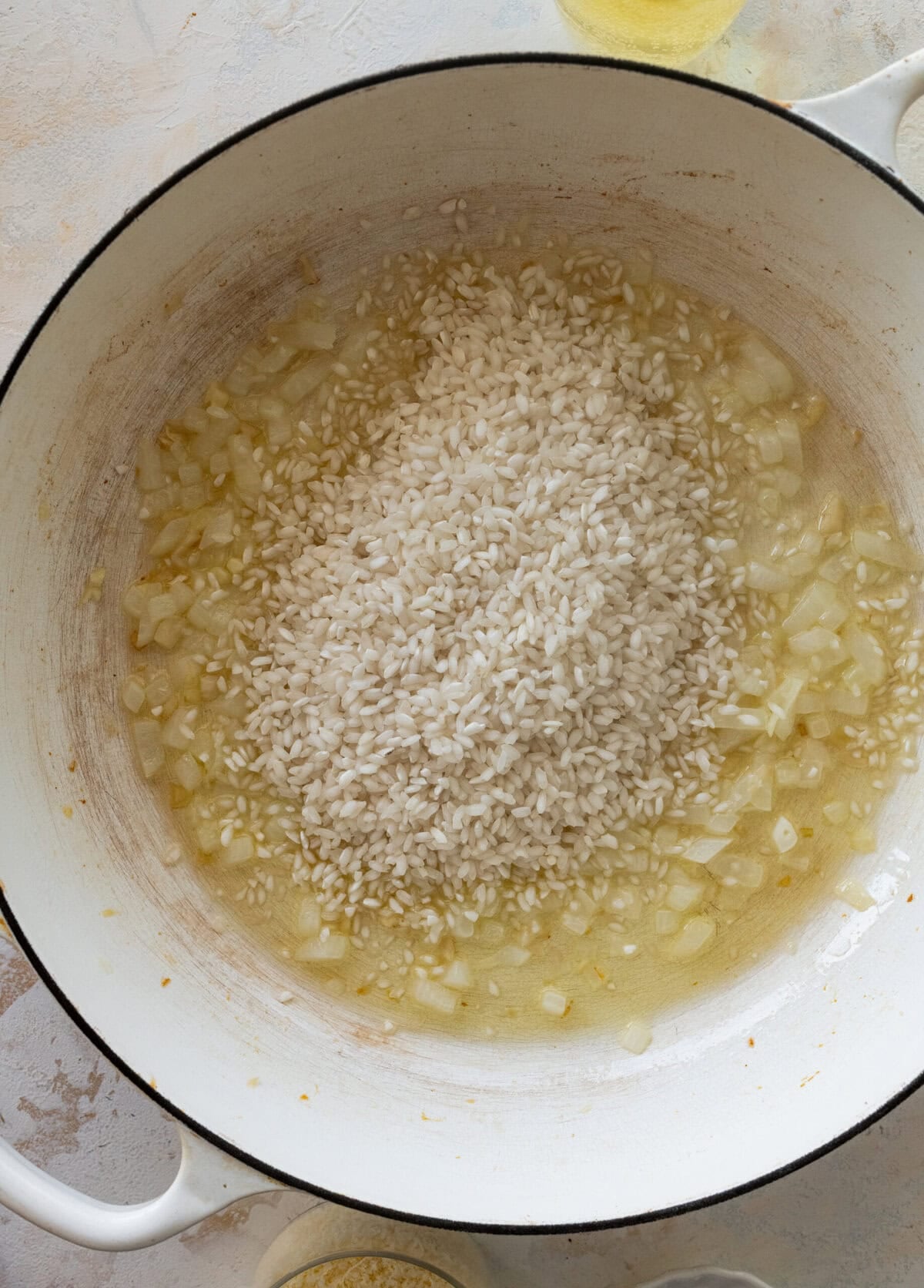 Rice, garlic, onion, and broth in a pot.