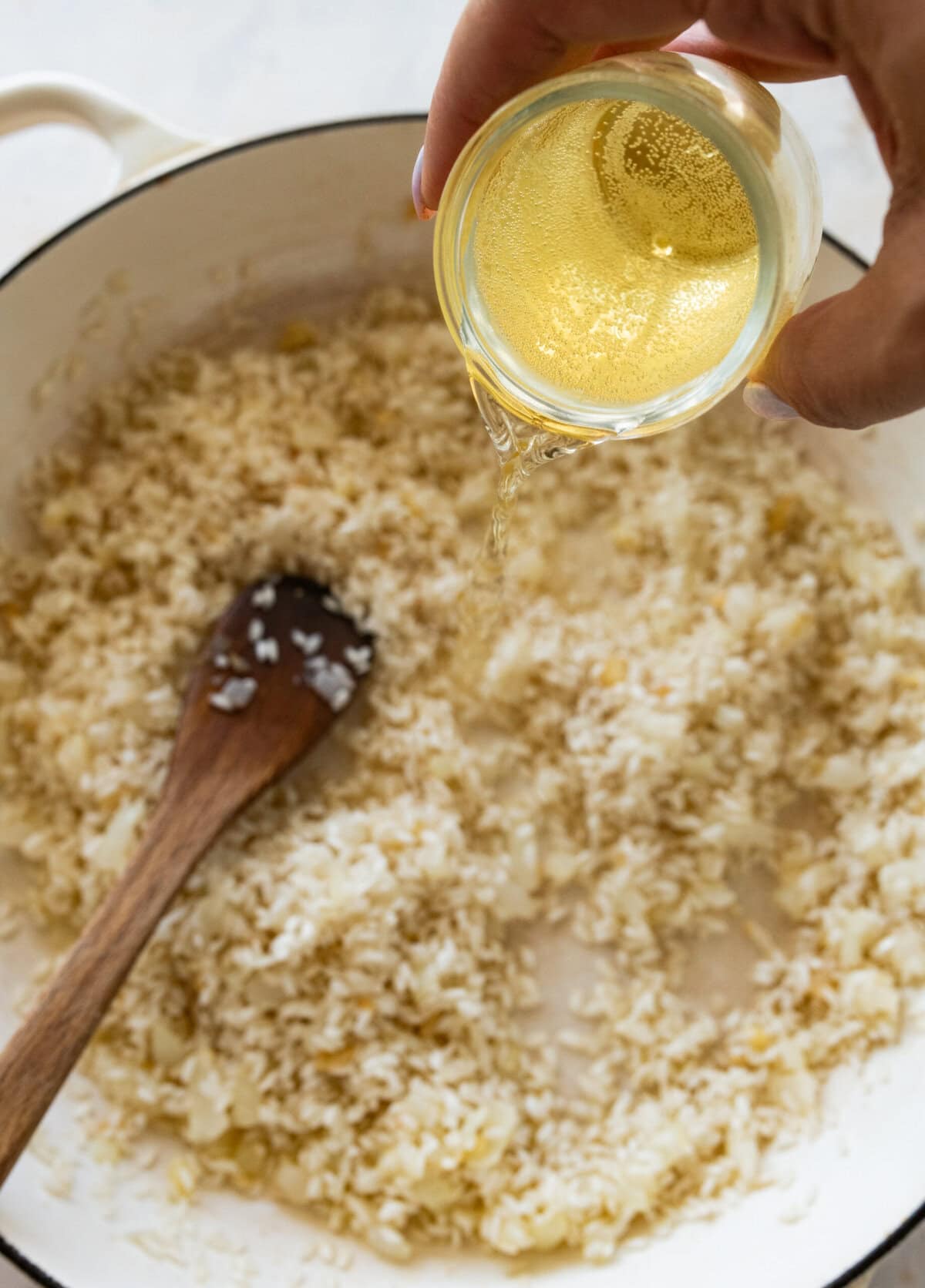 White wine being poured into the pot of rice.