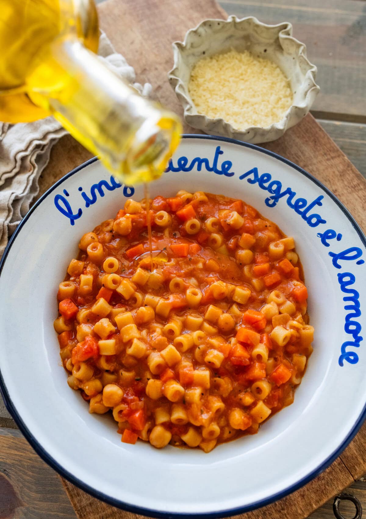 Olive oil being drizzled on top of a bowl of pasta e ceci.
