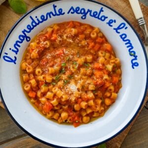 A bowl of pasta e ceci with more ingredients and utensils nearby.