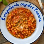 A bowl of pasta e ceci with more ingredients and utensils nearby.