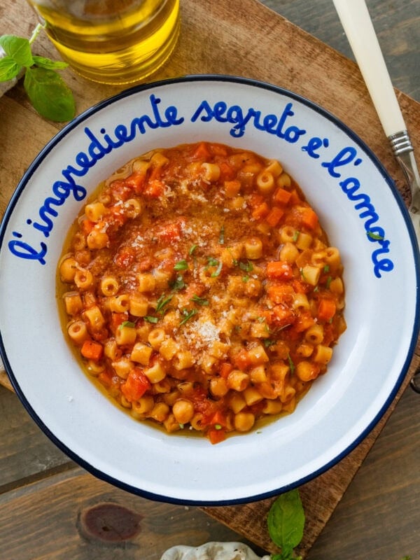 A bowl of pasta e ceci with more ingredients and utensils nearby.