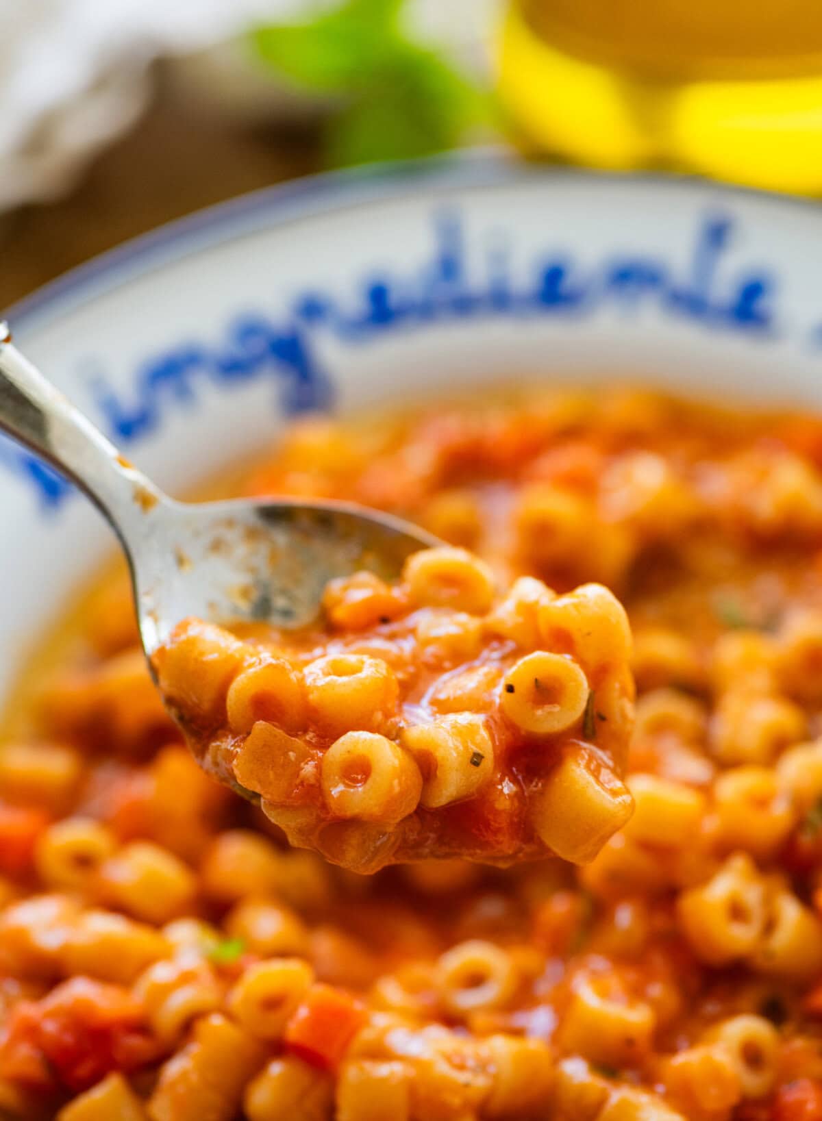 A bowl of pasta e ceci with a spoon holding a bite and more ingredients nearby.