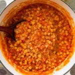 A pot of pasta e ceci with a ladle resting inside.