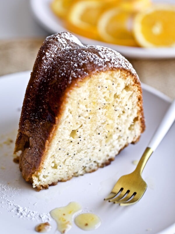 Fork on a plate with a slice of poppy seed cake with orange almond vanilla glaze.
