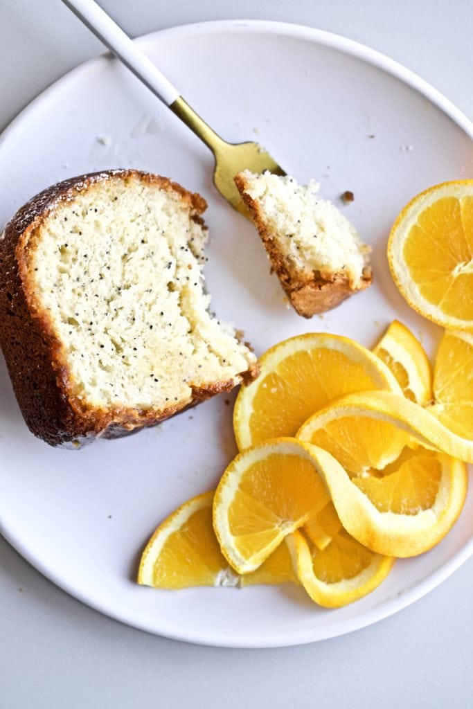 poppyseed almond cake with orange almond glaze slice on a plate with orange slices