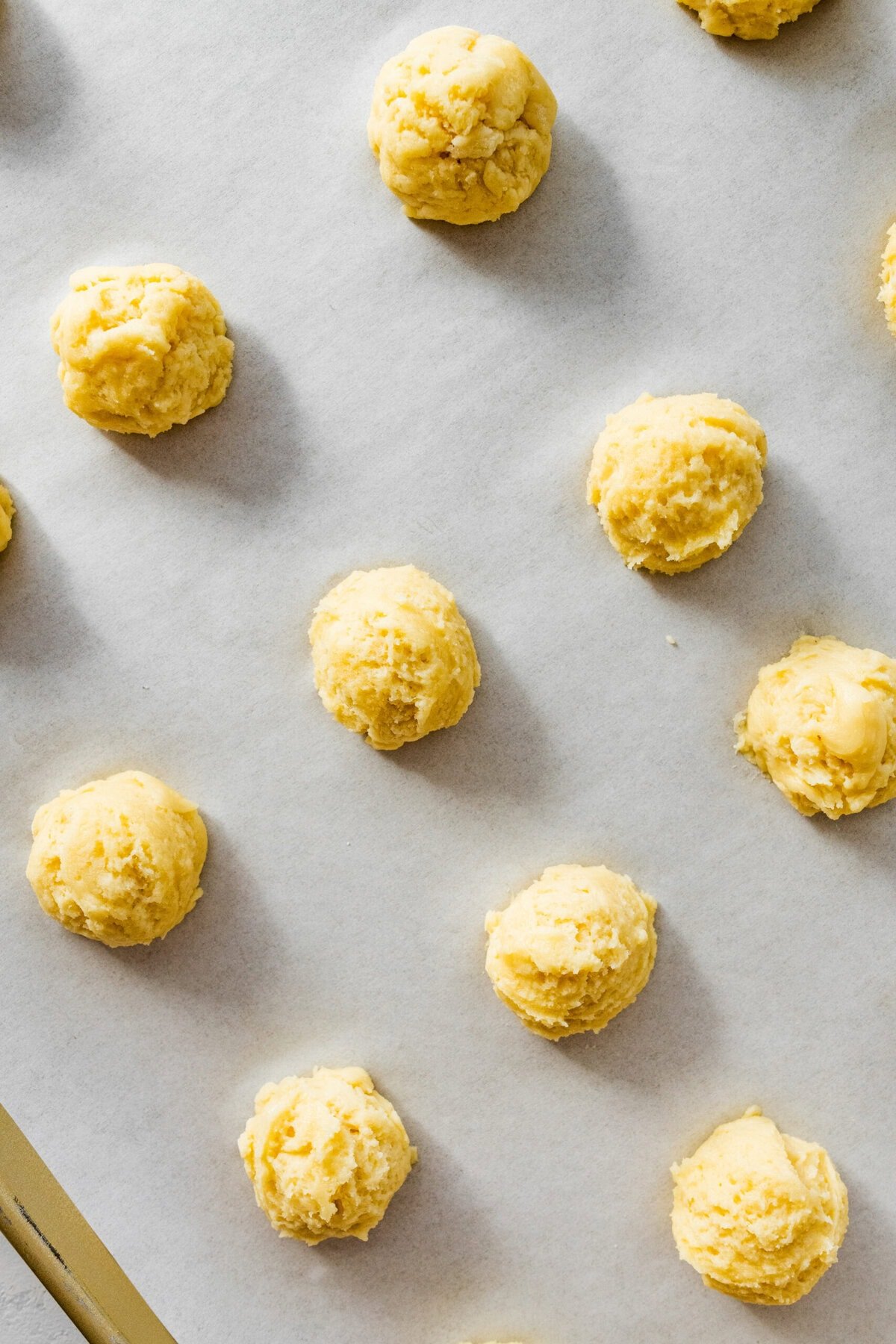 Anginetti cookie dough balls on a baking sheet.