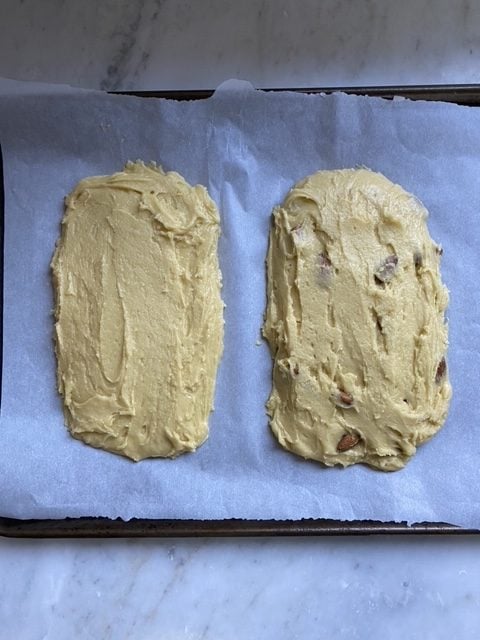 Two loaves of dough on a lined baking sheet.