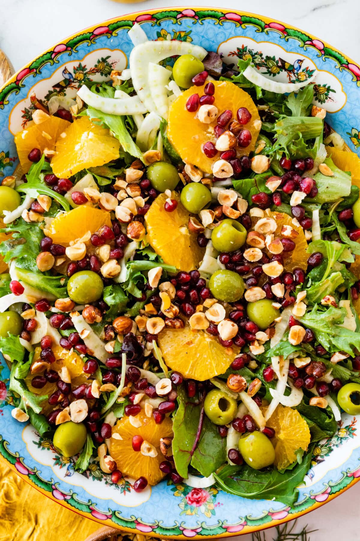 Italian orange fennel salad on a large serving platter with pomegranates and olives on the top.