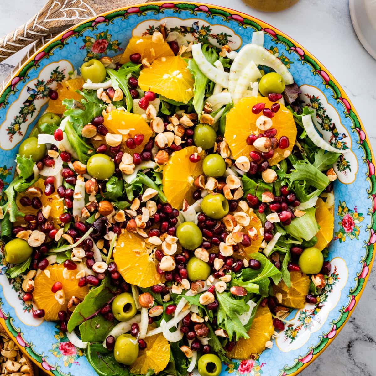 Italian orange and fennel salad with orange dressing on the side. Wooden salad servers on the side.