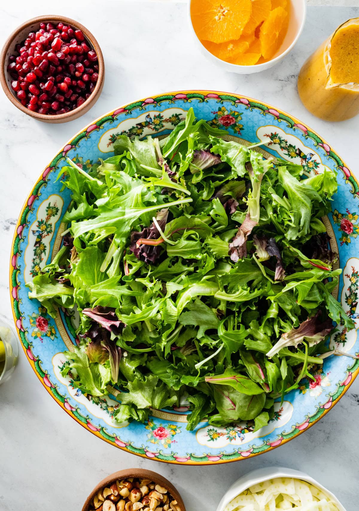 mixed greens in a large colorful blue serving bowl.