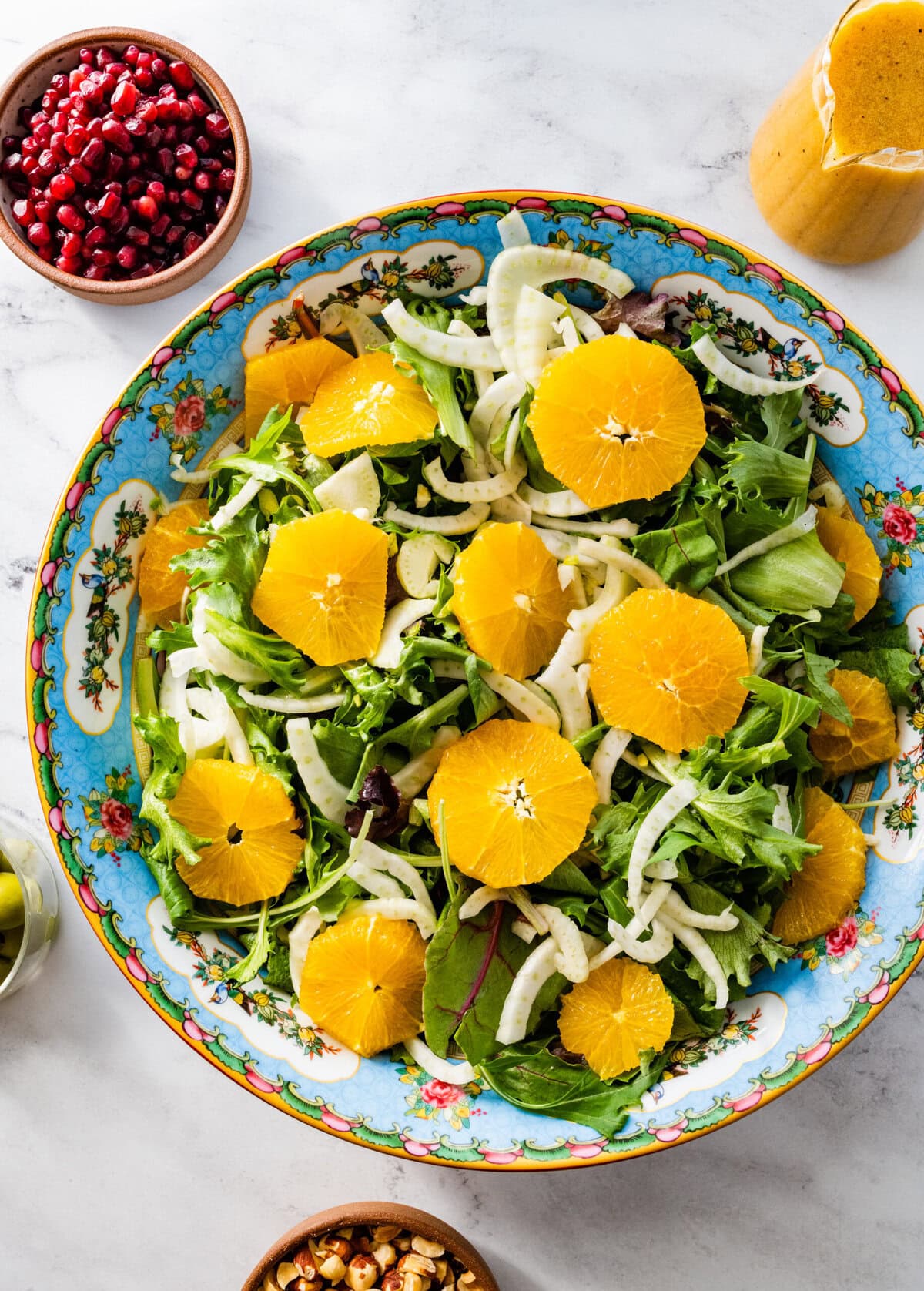 adding the orange and fennel to the salad mix in the salad bowl.
