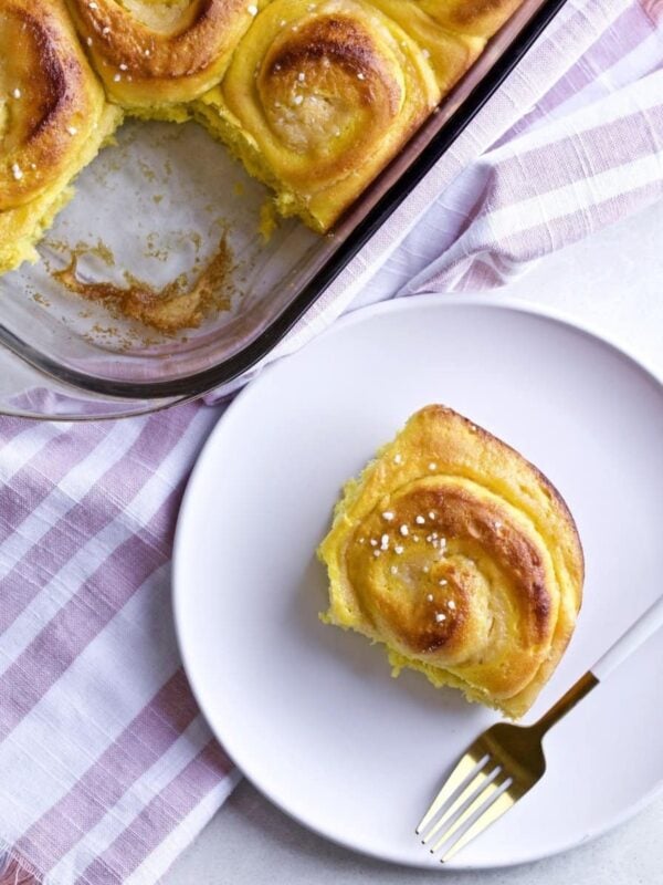St Lucia Bun on a plate with a fork and the rest in a baking dish nearby.