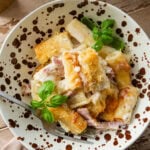 A bowl of ham and noodle casserole with a fork resting inside.