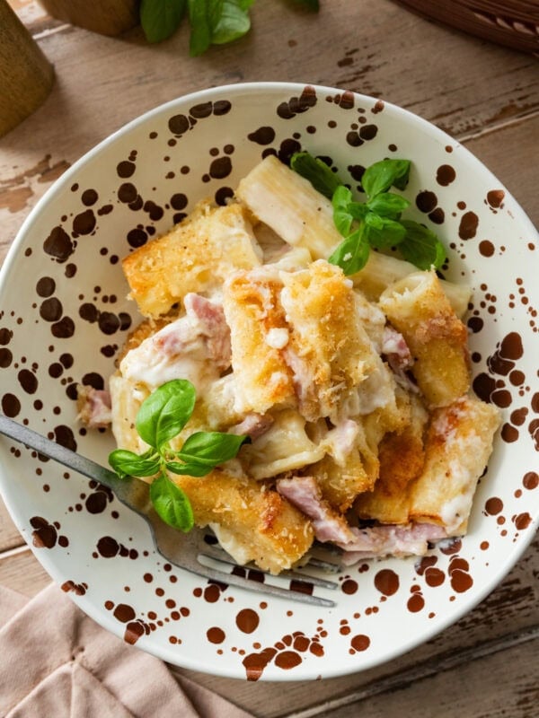 A bowl of ham and noodle casserole with a fork resting inside.
