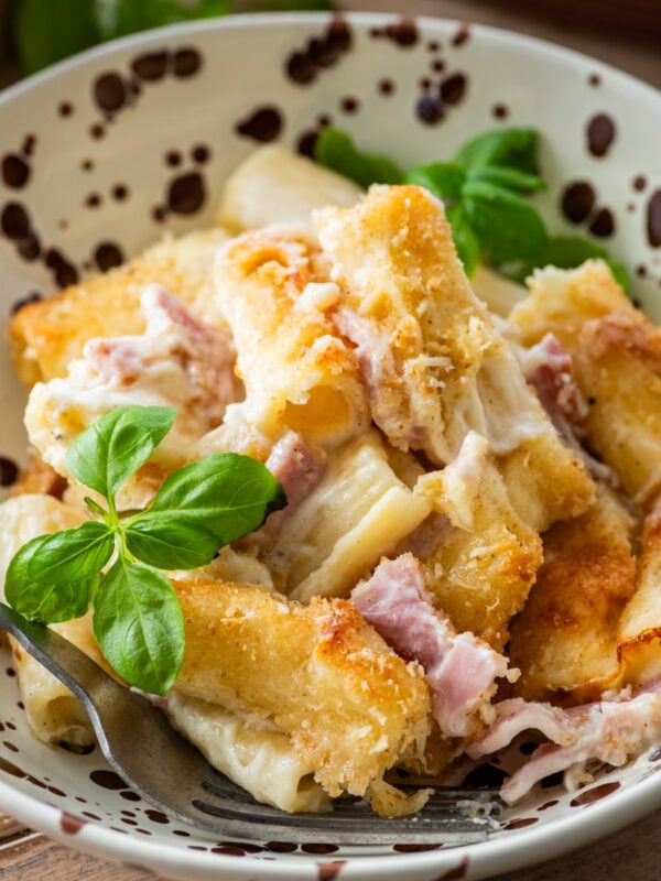 A bowl of ham and noodle casserole with a fork resting inside.
