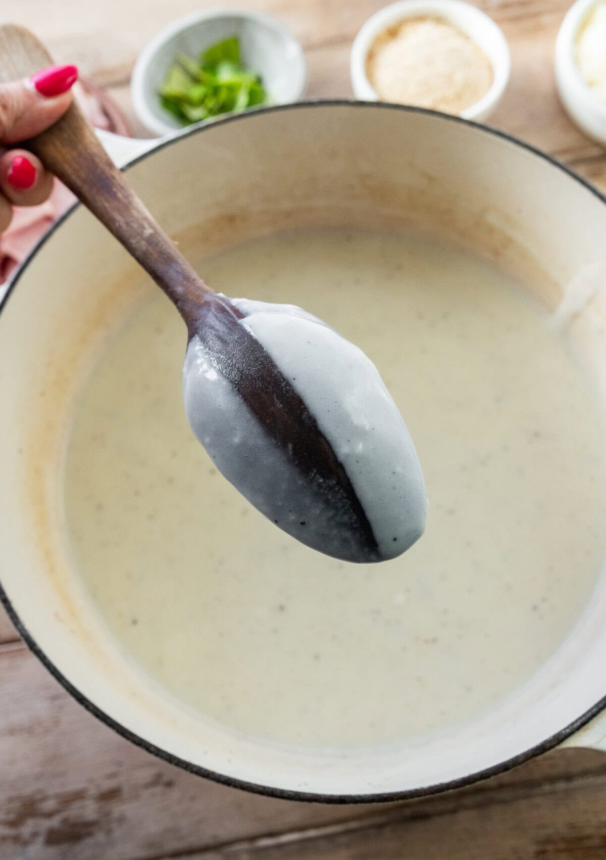 A spoon holding up the bechamel sauce.