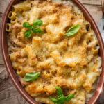 Ham and noodle casserole in a baking dish garnished with basil.