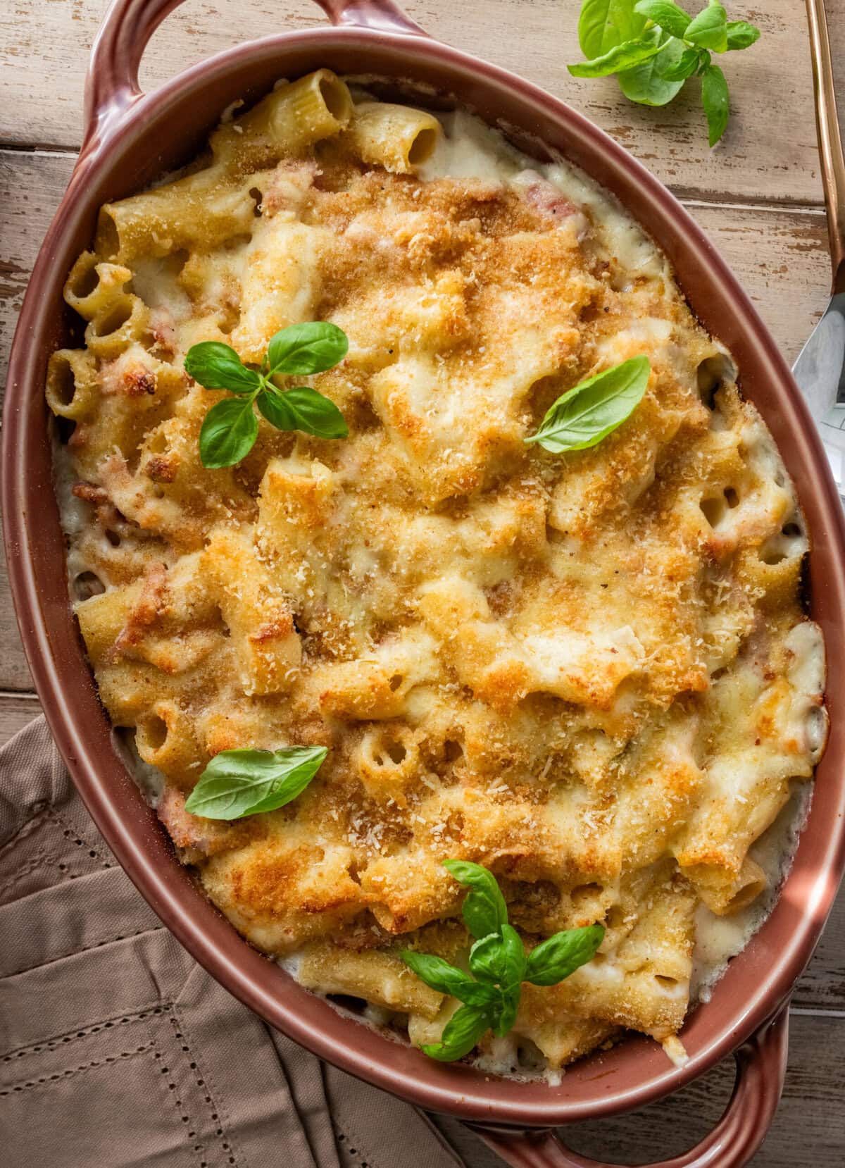 Ham and noodle casserole in a baking dish garnished with basil.