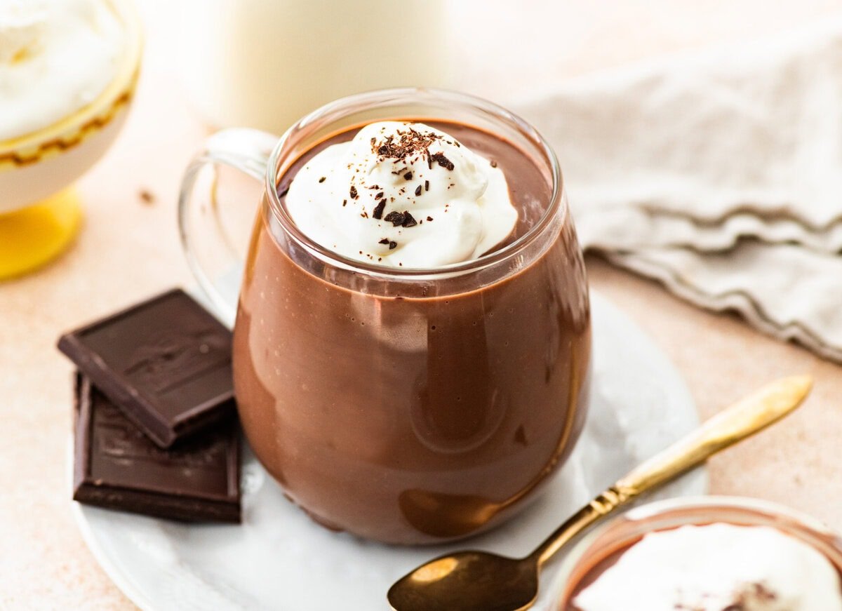 glass of Italian hot chocolate topped with whipped cream and a spoon.