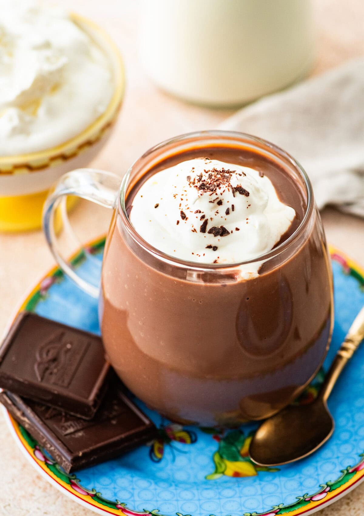 glass mug of hot chocolate with whipped cream and shaved chocolate.