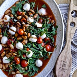 Warm white bean arugula salad mozzarella balsamic glaze in a large serving platter