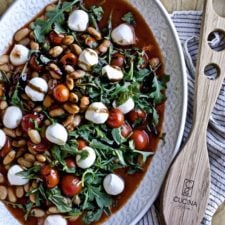 Warm white bean arugula salad mozzarella balsamic glaze in a large serving platter