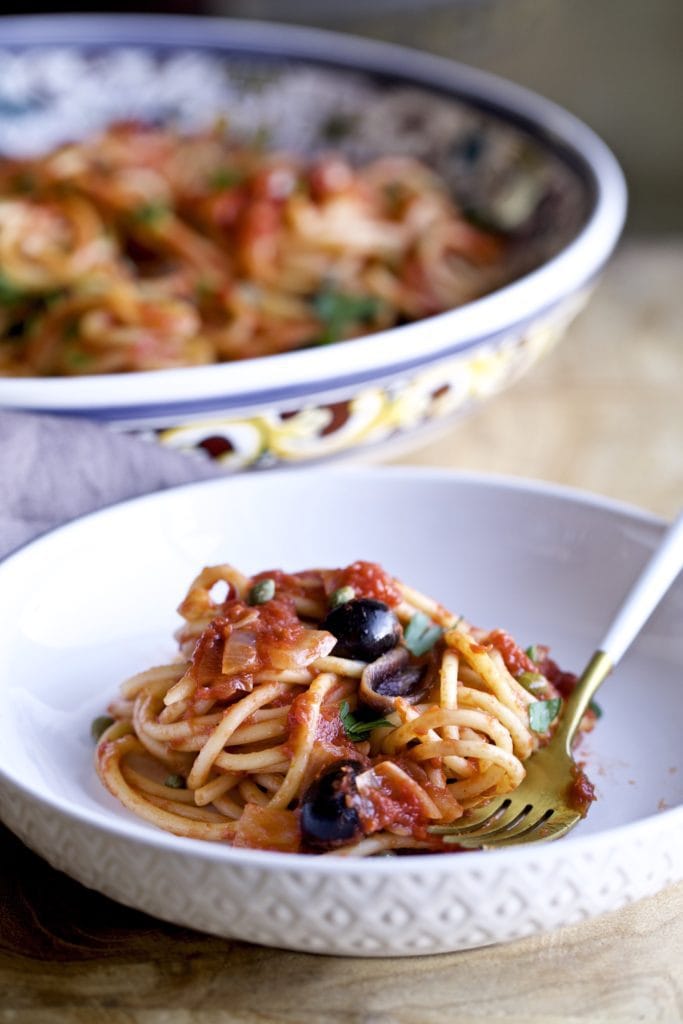 Spaghetti alla puttanesca in a bowl with a fork.