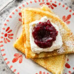 folded up swedish pancakes on a plate with toppings.