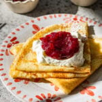 folded up swedish pancakes on a plate with toppings.