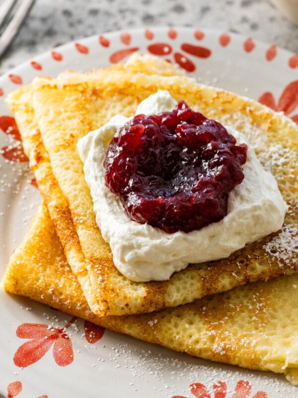 folded up swedish pancakes on a plate with toppings.