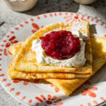 folded up swedish pancakes on a plate with toppings.