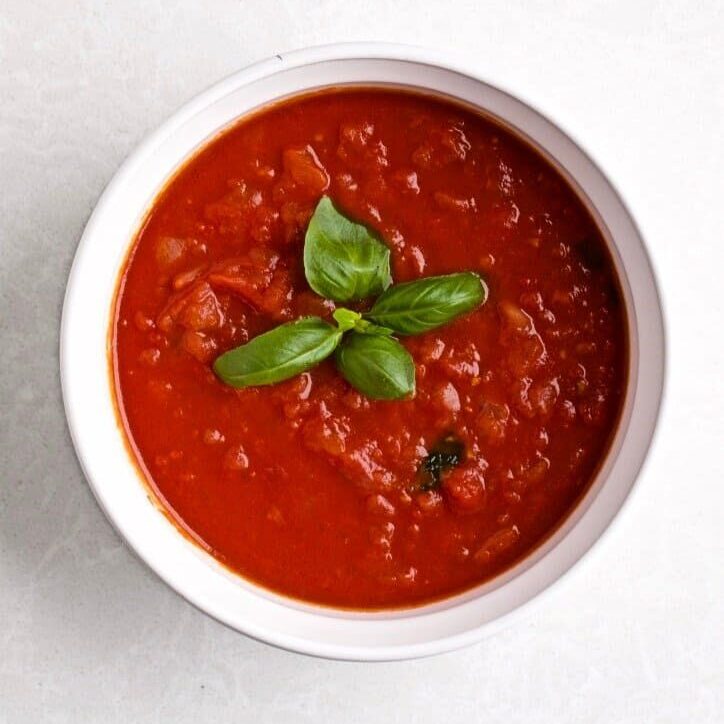 a bowl of classic Italian tomato sauce with basil leaves as garnish.