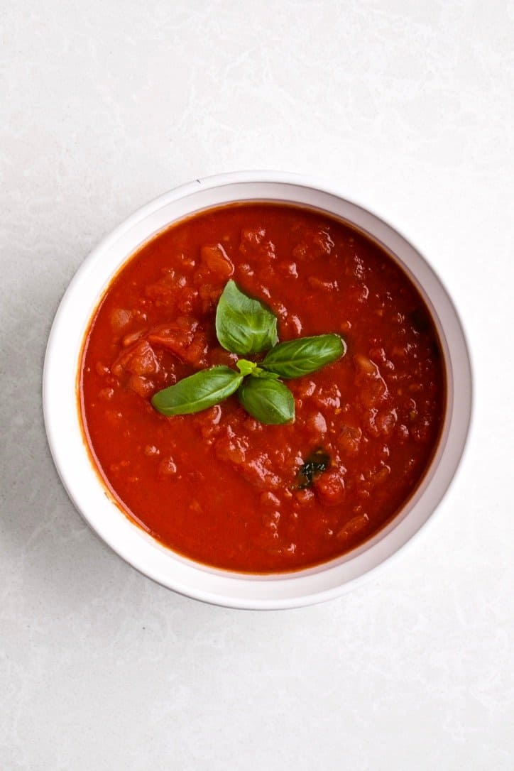 a bowl of classic Italian tomato sauce with basil leaves as garnish.