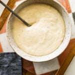 finished bechamel sauce in serving bowl with a spoon in it.