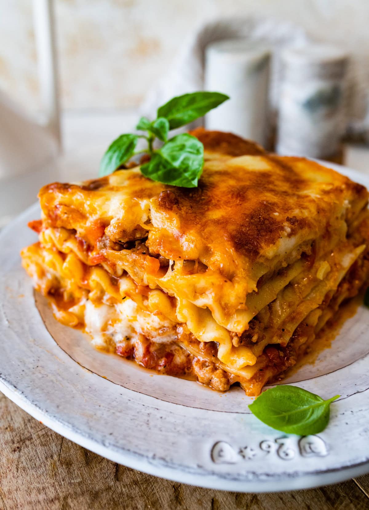 slice of lasagna with basil leaves on the side.