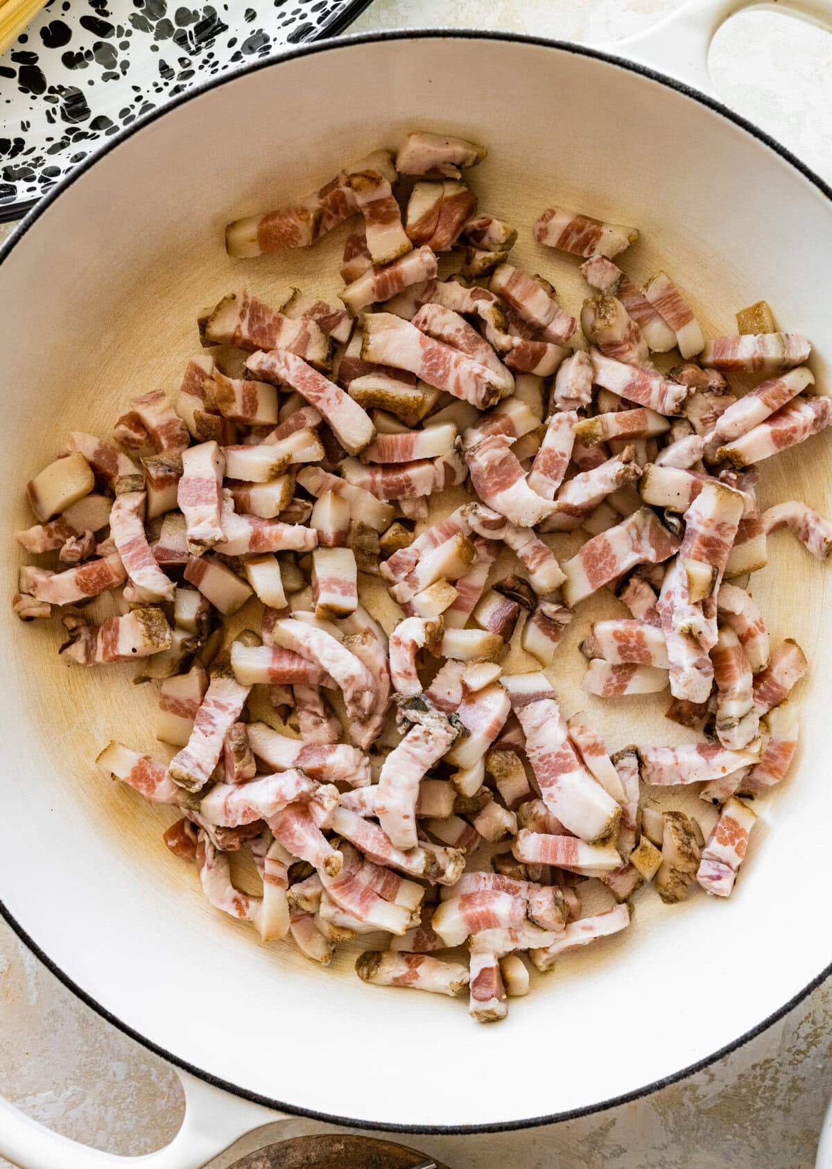 Guanciale added to a skillet to cook.