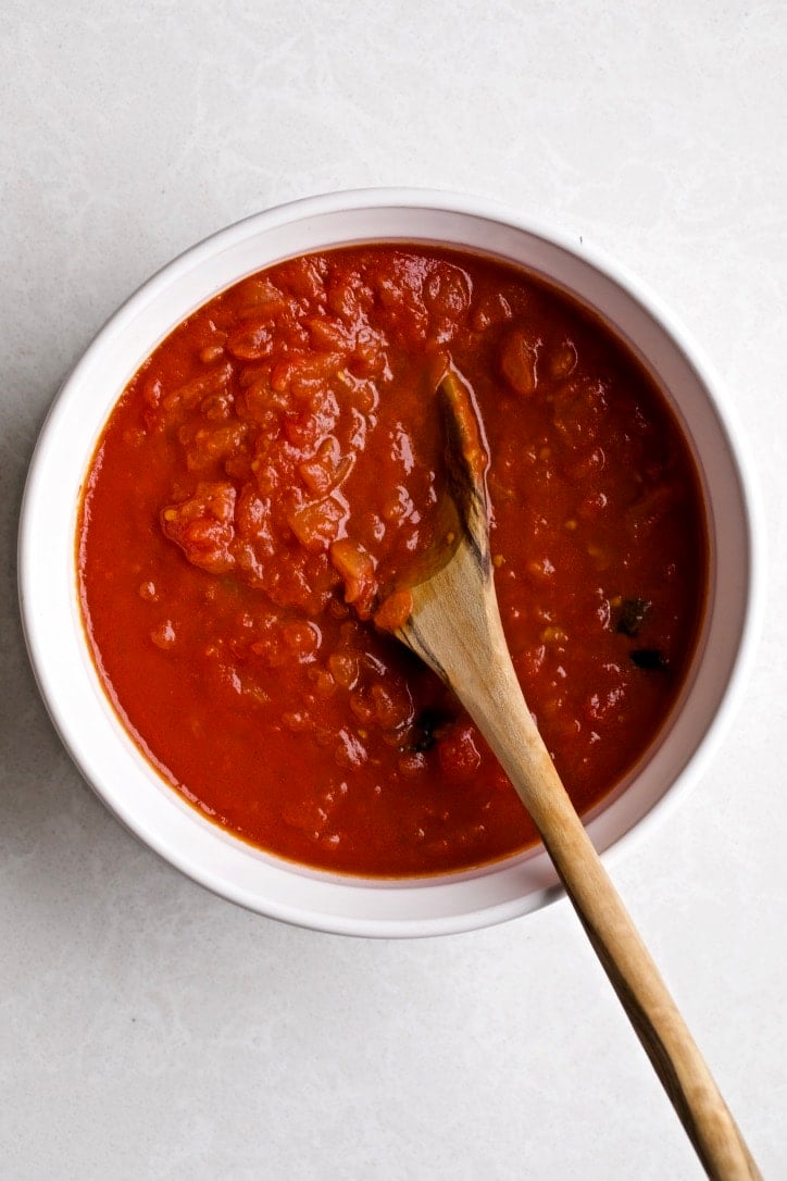 a bowl of classic Italian tomato sauce with a wooden spoon in it.