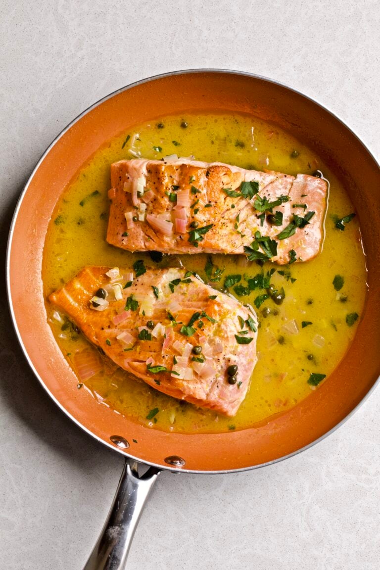 Salmon in Lemon Butter Caper Sauce (Salmon Piccata) in a pan with the delicious sauce and a garnish of parsley.