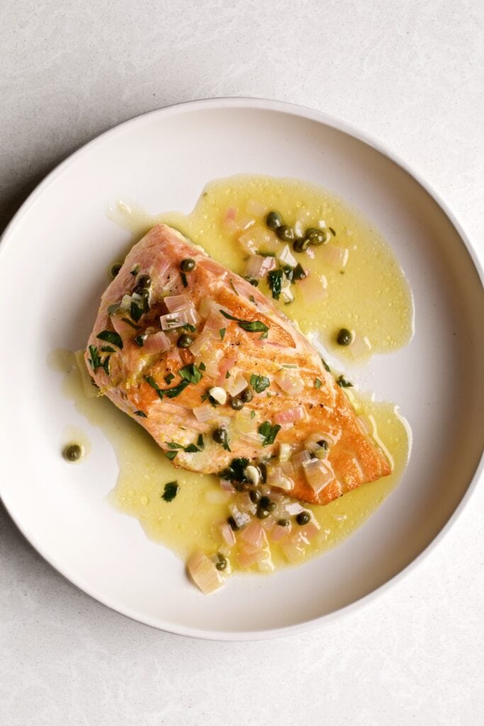 Salmon Piccata with lemon sauce on a white plate.