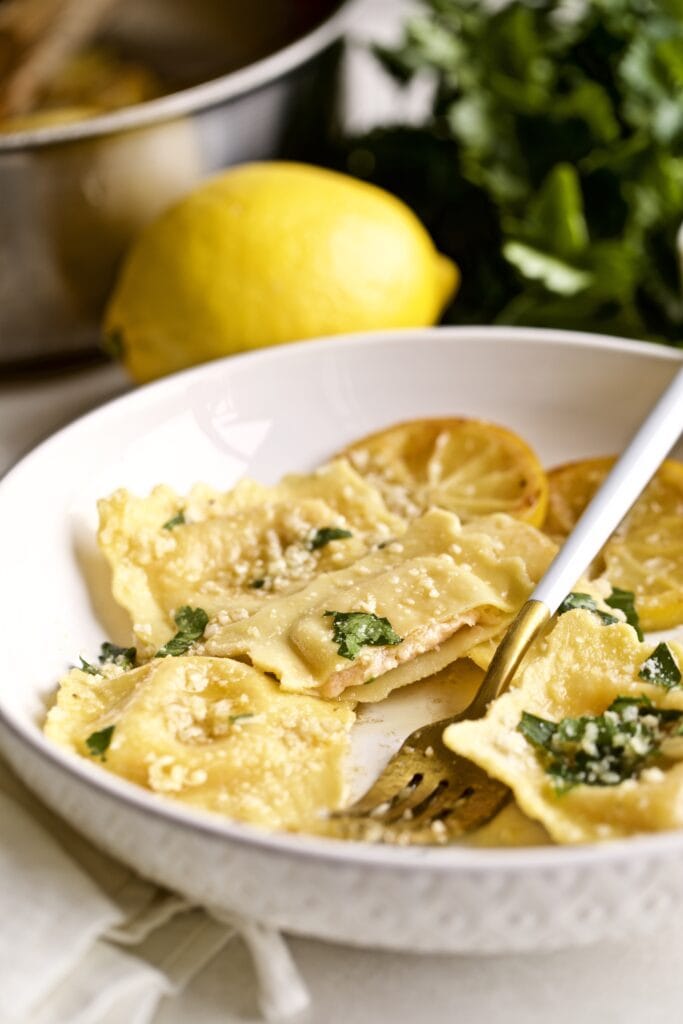 Lobster ravioli in a white bowl with a fork.