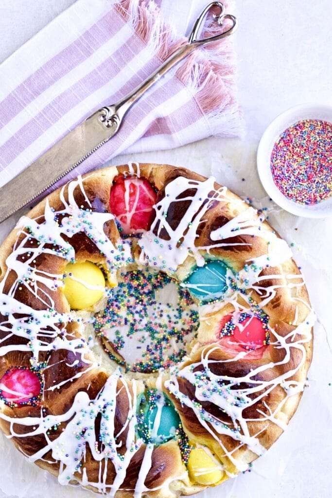 Finished Easter bread dough with a knife and sprinkles on a white background.