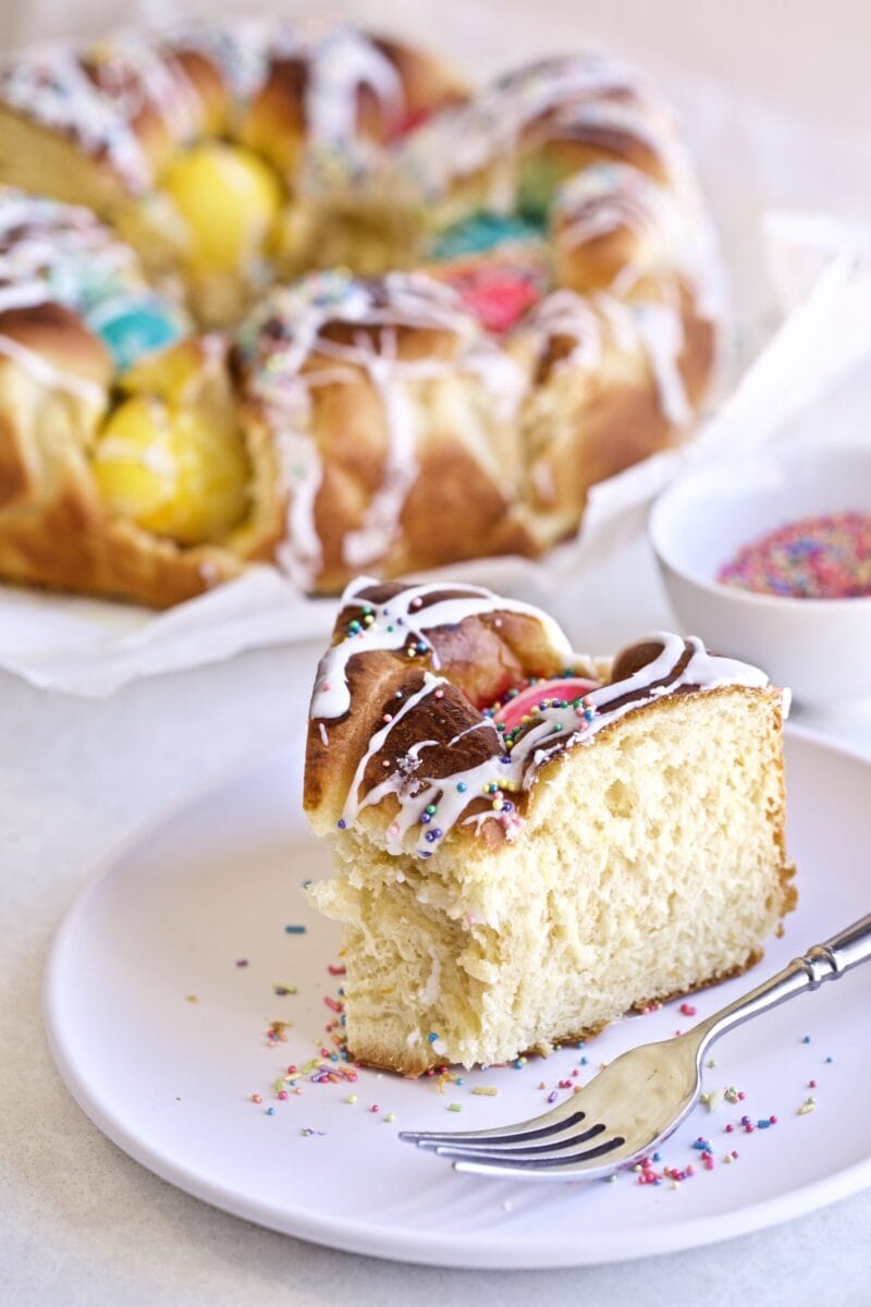 Bread Easter Bread Recipe (Italian) . Slice of thick and soft brioche bread on a plate with large cake in background.