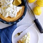 Best Italian Ricotta Pie Recipe (Easter) with whipped cream in a beautiful pie dish one slice is cute out and lemons in the background.