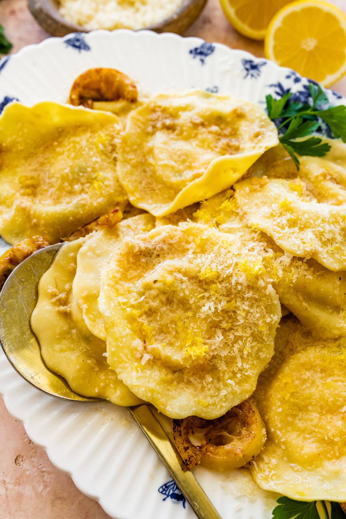 Lobster ravioli sauce and ravioli on a plate with a spoon to the side.