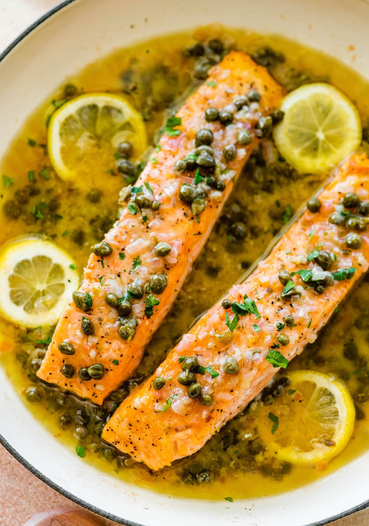 Lemon caper butter salmon in a white dish.