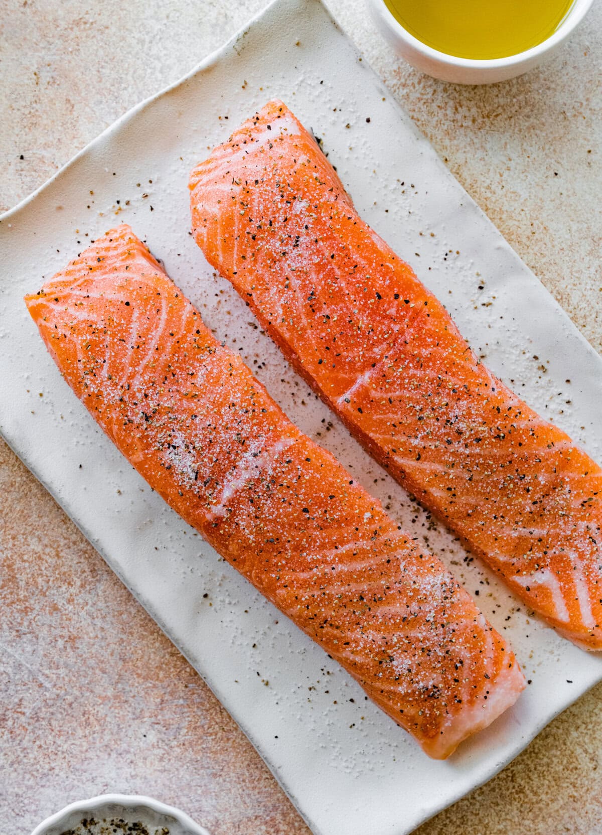 Seasoned salmon fillets on a paper towel.