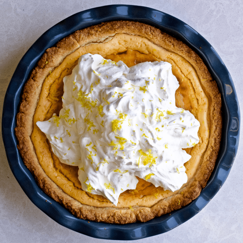 Italian ricotta pie in a dark blue dish with whipped cream on top.