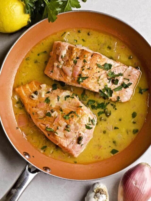 Salmon in Lemon Butter Caper Sauce (Salmon Piccata) in a pan with the delicious sauce and a garnish of parsley.